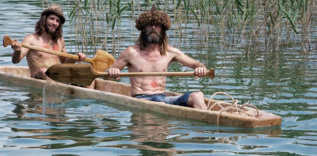 Zwei Männer mit Ruder in der Hand in einem handgeschnitzen Boot auf dem Wasser