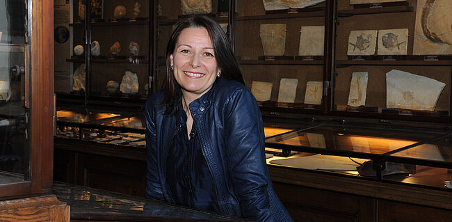 Ursula Göhlich lehnt an einer Vitrine im NHM Wien
